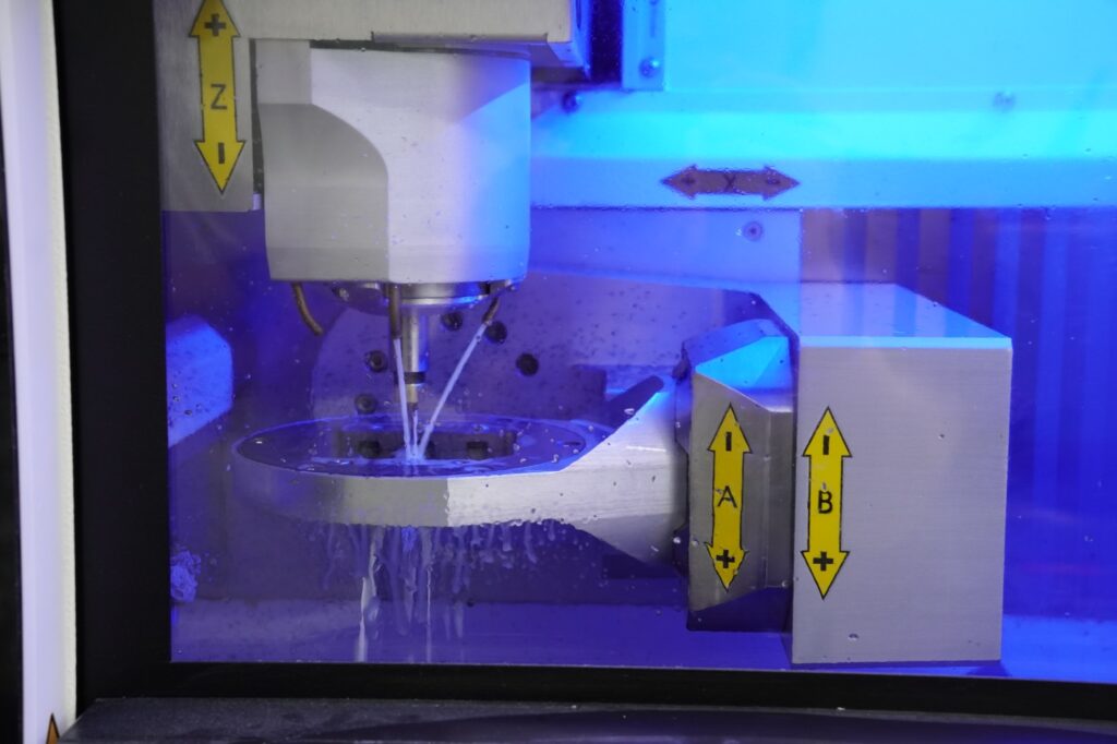 Milling chamber of the imes-icore CORiTEC 350i PRO at Khai Nguyen Dental Lab during wet milling, showing the Z, X, A and B axes